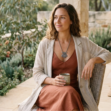 Woman sitting outdoors holding a cup, surrounded by nature