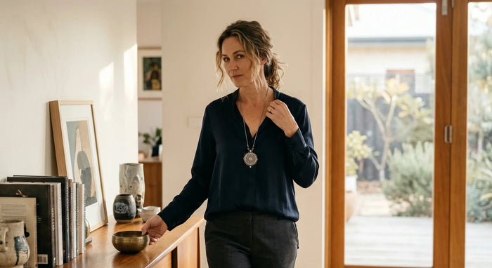 Woman standing in a room with a wooden dresser and sliding glass door.